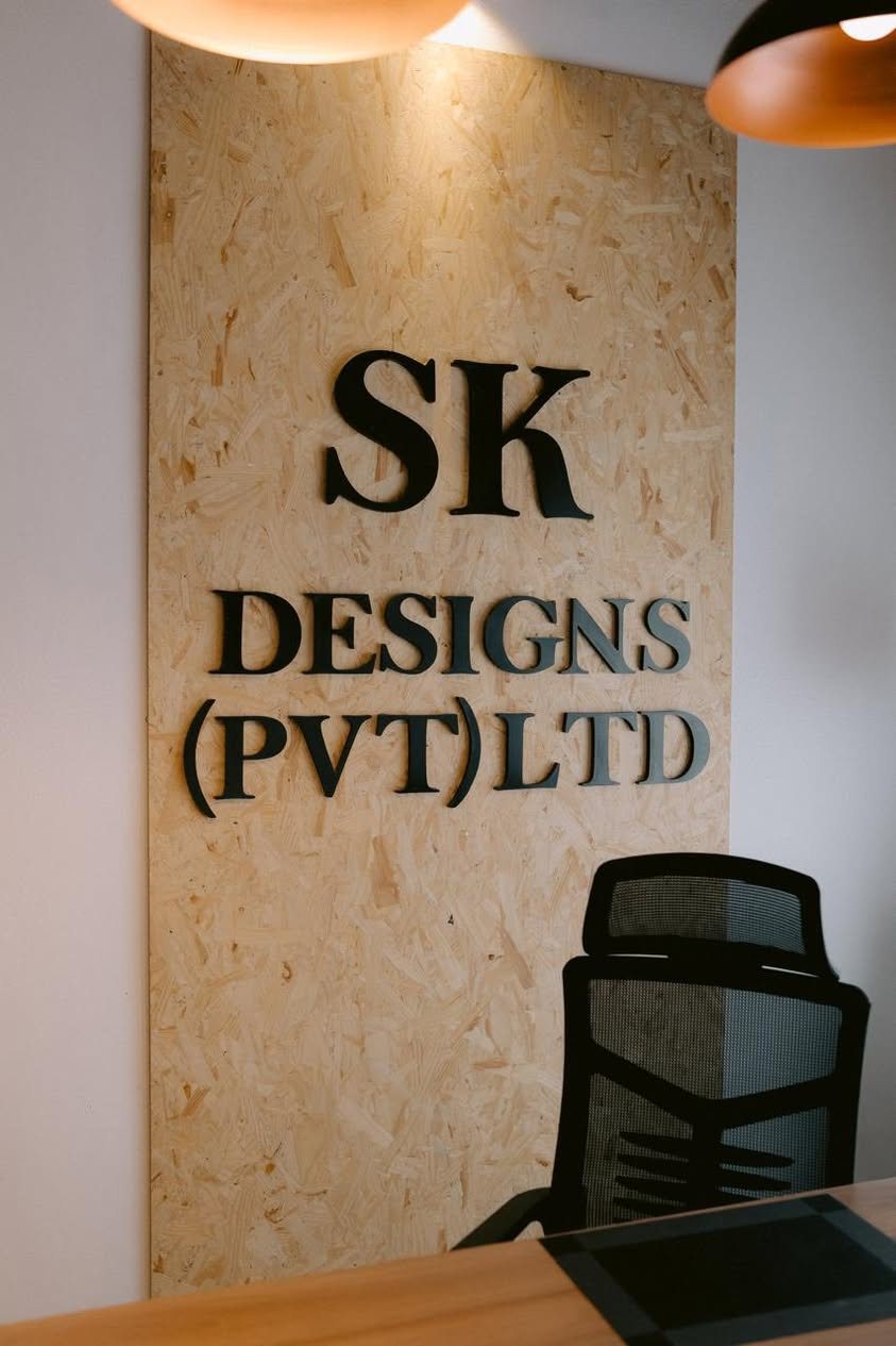 Cut black lettering reading SK Designs (Pvt) Ltd mounted on an oriented strand board panel